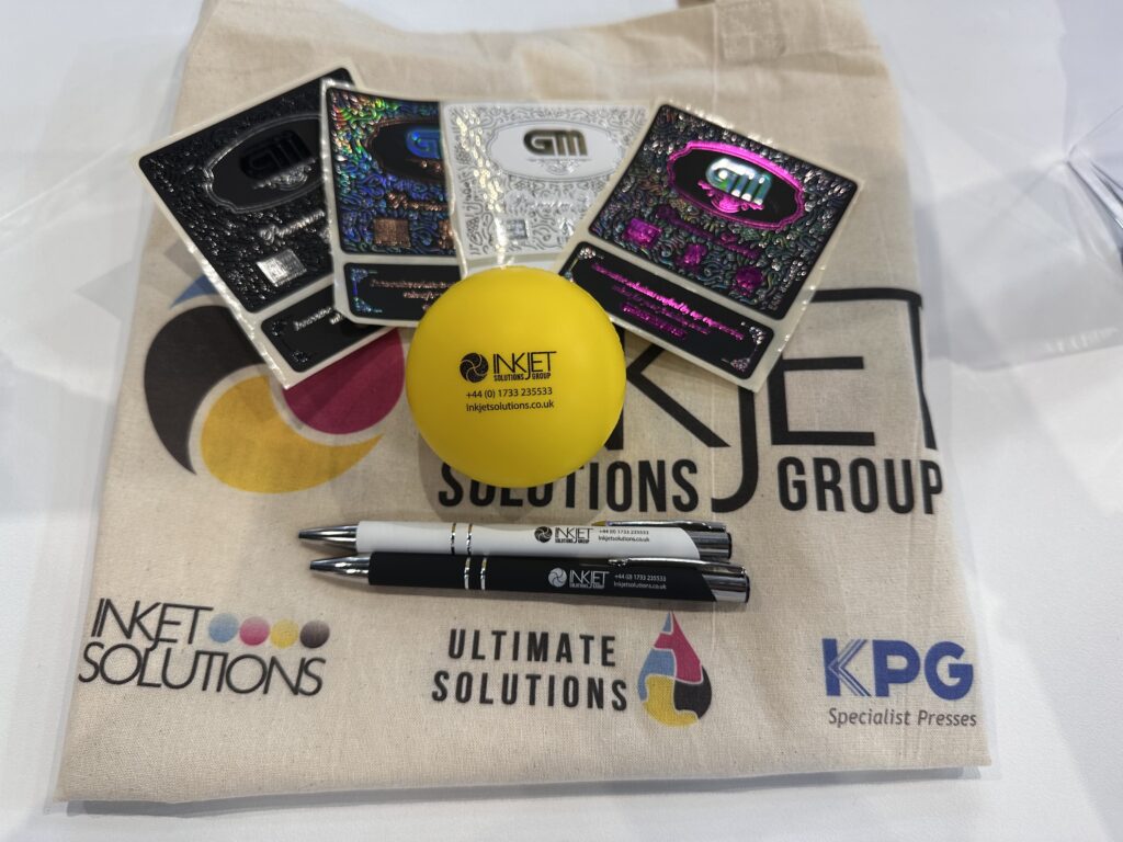 Inkjet Solutions merchandise featuring a tote bag, pens, stress ball and label samples.